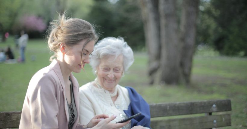 daughter explaining elderly mother how using smartphone