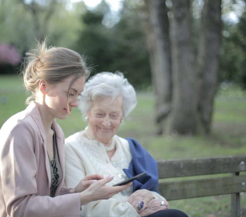 daughter explaining elderly mother how using smartphone