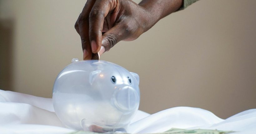 person putting coin in a piggy bank
