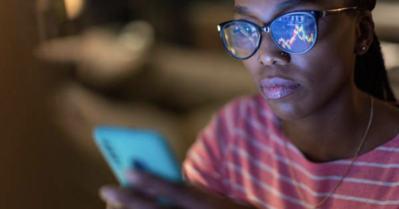 Diverse investment strategy illustration showing woman using investing app toward upward trending graphs.