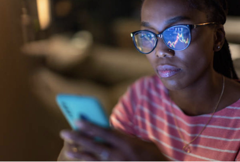 Diverse investment strategy illustration showing woman using investing app toward upward trending graphs.