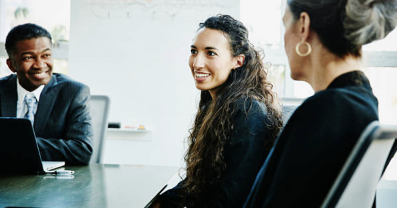 Professional PR manager leading virtual team meeting in modern office setting, displaying multiple digital communication channels.