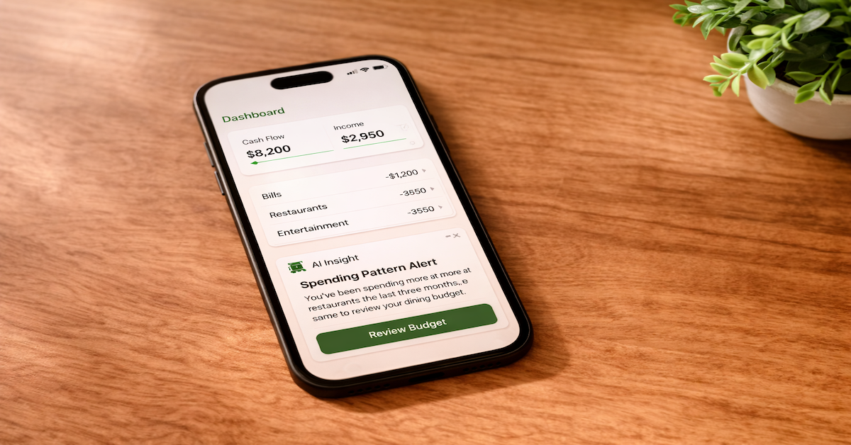 Smartphone displaying a financial dashboard with an AI insight card showing a spending pattern alert on a warm wood desk