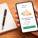 Hand holding a smartphone showing a financial app onboarding screen step 3 of 6 beside a checklist notebook on a wood surface