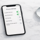 Smartphone showing a privacy settings screen with toggle switches beside a small magnifying glass on a white marble surface