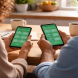 Two people sitting at a kitchen table each viewing matching budgeting app dashboards on their smartphones