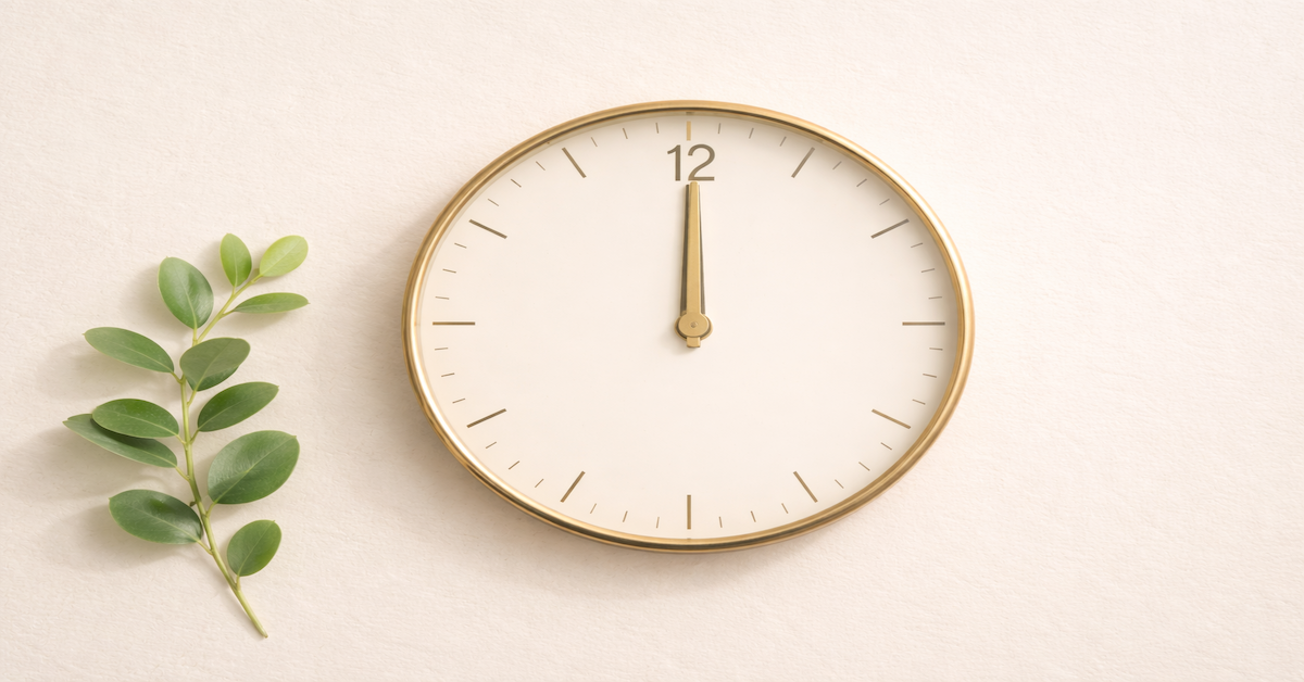 An analog clock face beside a small green plant on a clean cream surface, representing the time it takes to build a 700 credit score — a 12 to 24 month process driven by consistent payment behavior and the right credit tools