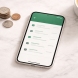 Smartphone displaying a banking transaction dashboard on white marble surface with coins beside it