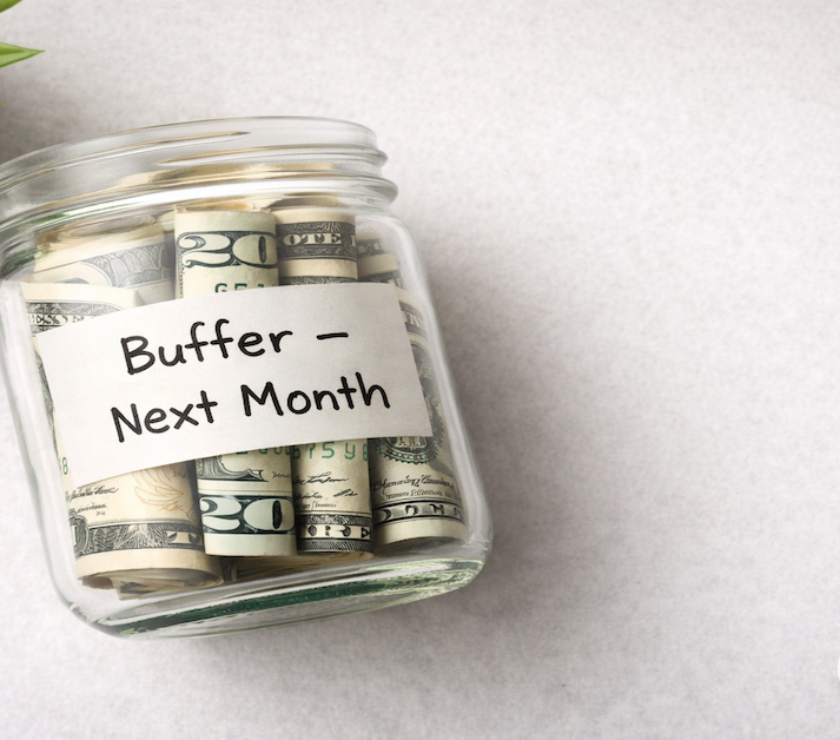 Glass jar two-thirds full of rolled bills labeled Buffer Next Month on a light gray surface — PersonalOne